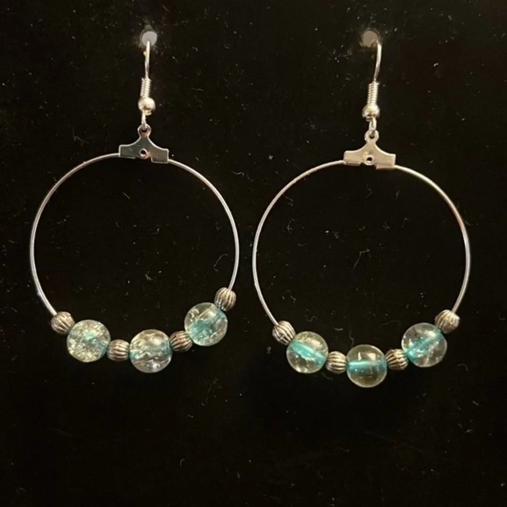 Handcrafted silver tone hoop earrings with clear and blue beading.